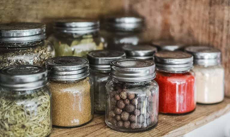 Close-up of assorted spice jars with various herbs on a kitchen shelf, showcasing colorful culinary ingredients.