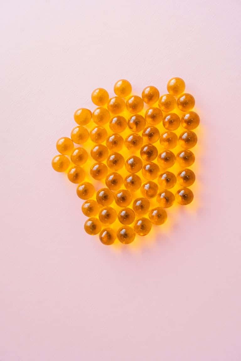 Close-up of yellow capsules on a pink background, showcasing health and vitality.