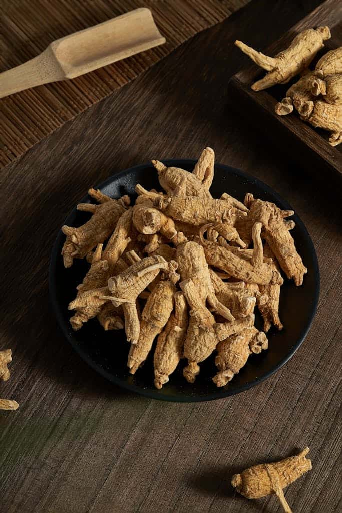 Detailed shot of dried ginseng roots on a dark plate for natural healing and cooking.