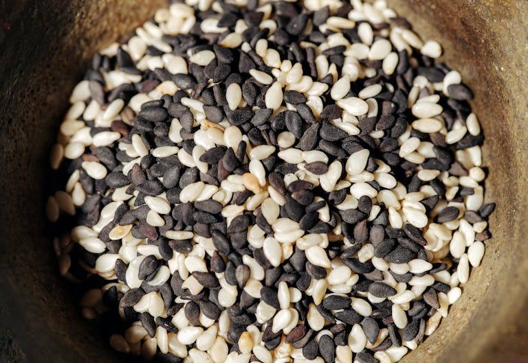 A detailed close-up of black and white sesame seeds in a rustic bowl, perfect for healthy food themes.